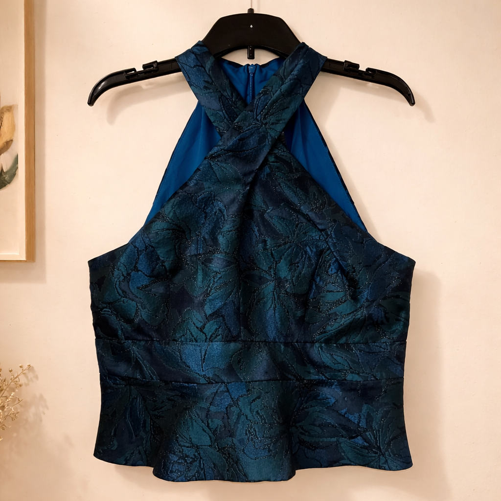 Sleeveless top by Muse is defined by its dramatic criss-cross halter neckline and structured silhouette. Size 16