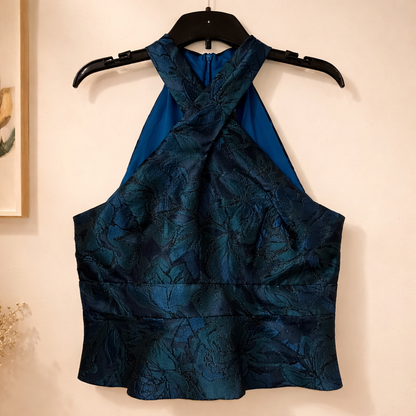 Sleeveless top by Muse is defined by its dramatic criss-cross halter neckline and structured silhouette. Size 16